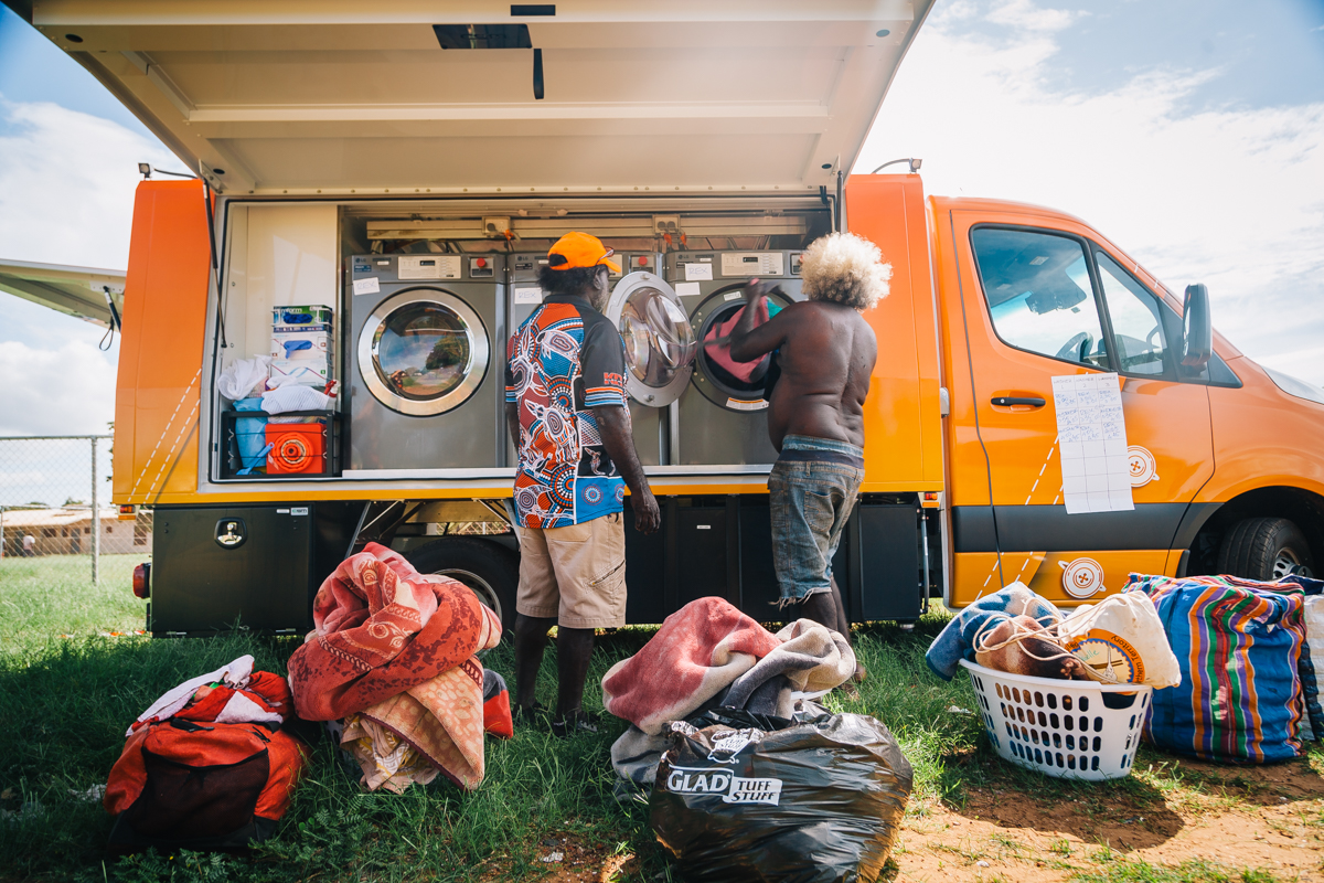 remote resident and volunteer putting washing in orange washing van in remote community