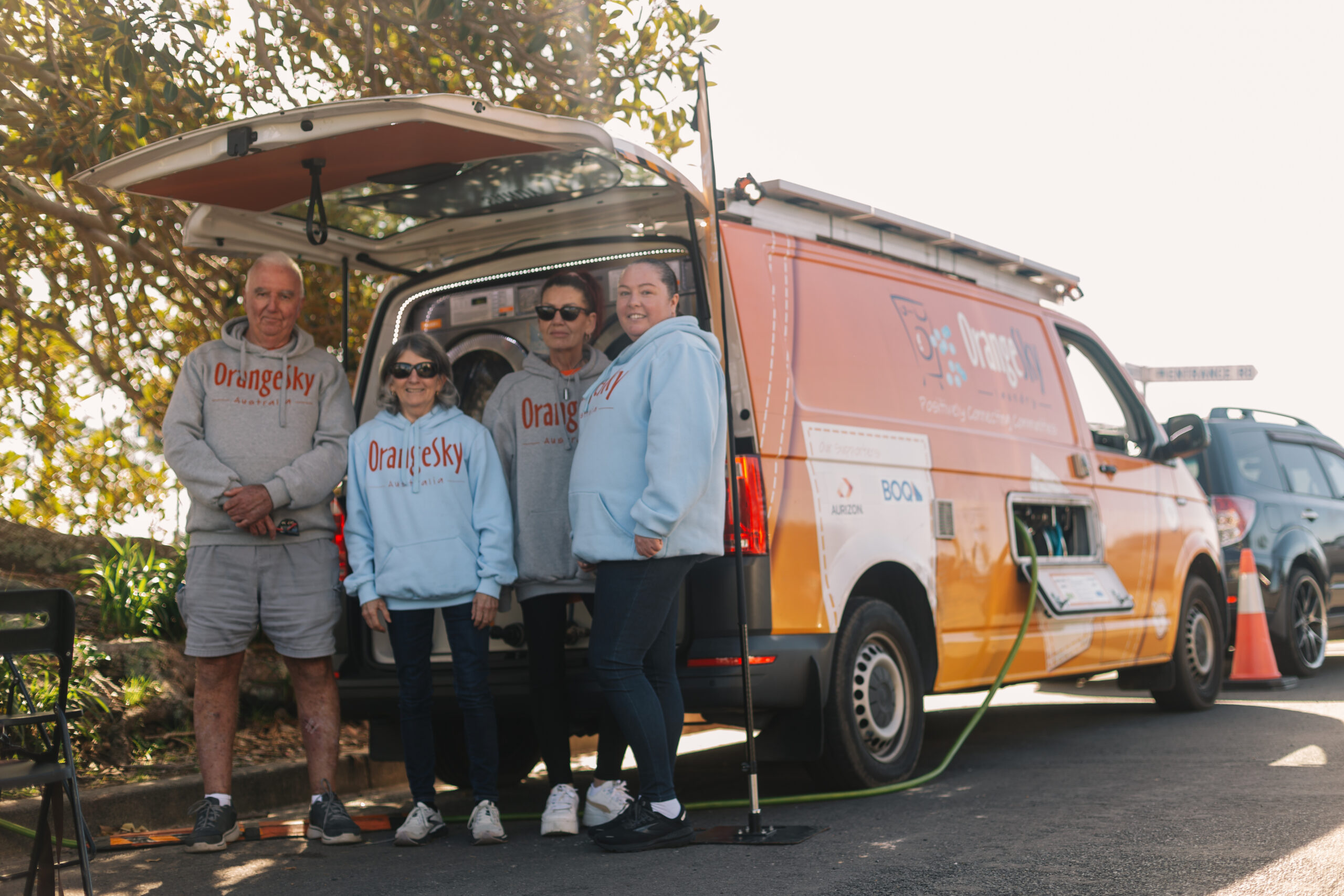 Amanda standing with other Orange Sky Volunteers after being homeless in front of Orange Sky van